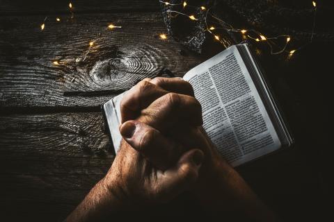 Hands resting over an open Bible