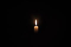 A single lit candle in the darkness