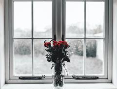 Bouquet of dried red roses in from of a window with snow outside
