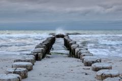 wooden pillars leading out to a rough sea